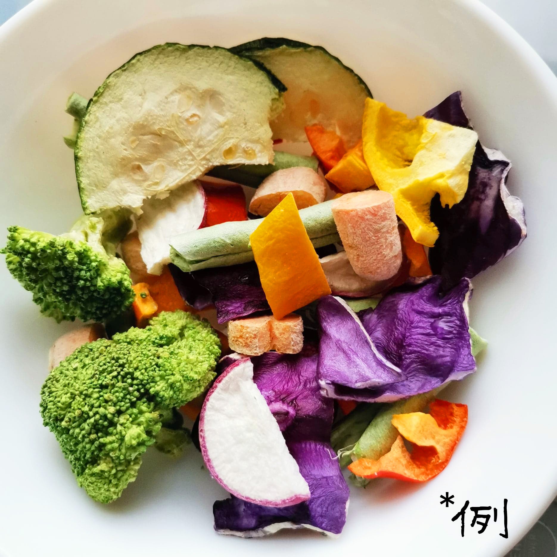 白い器に入ったフリーズドライのバードフード、ブロッコリー房や大根スライス、かぼちゃ片が確認できる野菜中心の構成